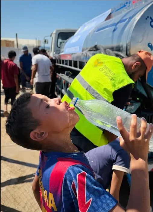 Junge trinkt Wasser aus einer Flasche in Gaza